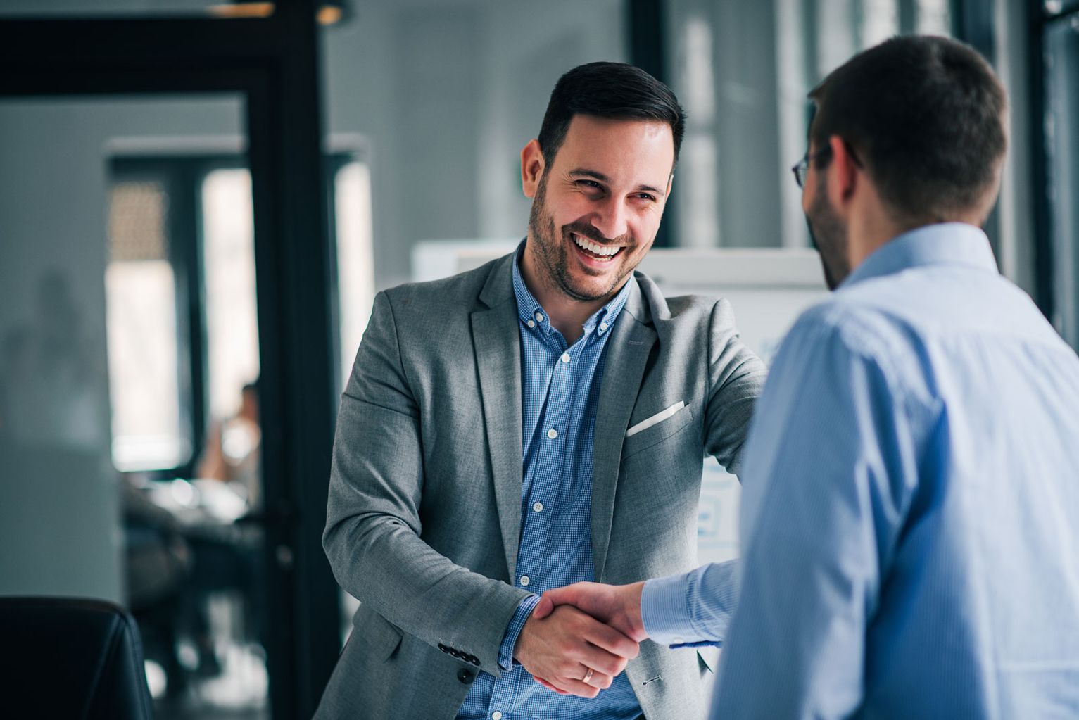 Two men shake hands in an office, symbolising cooperation and professional exchange